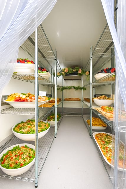 Catering food platters and salads stored inside refrigerated trailer for wedding or event rental